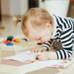 Little girl draws with pencils. Child development.
