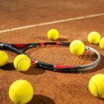 Racket and scattered tennis balls on the court