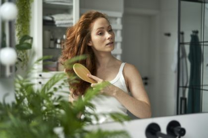 Redhead woman brushing hair in the bathroom