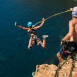 Rope jumping off a cliff with a rope in the water. The ocean. Sea. Mountain.
