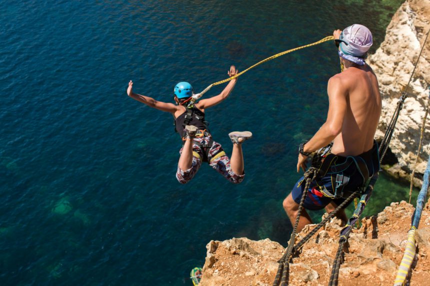 Rope jumping off a cliff with a rope in the water. The ocean. Sea. Mountain.